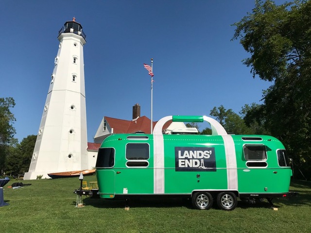Green Airstream trailer near white lighthouse